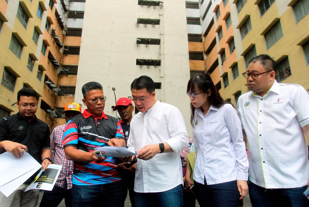 Kor Ming (tengah) melihat kertas Laporan Program Penyelenggaraan Perumahan (PPP) ketika mengadakan lawatan ke Rumah Pangsa Seri Kepayang, Ipoh pada Sabtu.