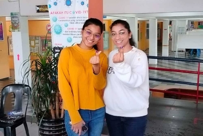 Pavitrawini (kiri) bersama kakaknya, Keiswini menunaikan tanggungjawab mengundi pada PRK Parlimen Pulai di SMK Taman Bukit Indah pada Sabtu.