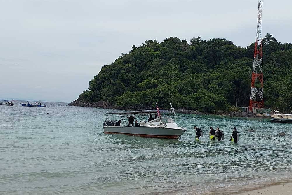 Pengunjung sedang menaiki bot untuk melalukan aktiviti selaman di sekitar Pulau Tenggol