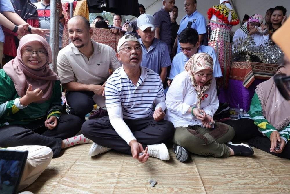 Yang di-Pertuan Agong dan Raja Permaisuri berkenan bermain batu seremban. - Foto Bernama