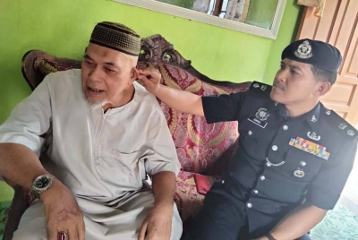 Mohamad Ismail (kanan) melihat telinga Mohd Yusof yang ditembusi peluru dalam kejadian serangan komunis sebulan selepas tragedi 13 Mei 1969.