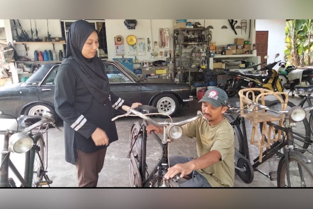 Mohd Hafizal dan Nurul Adilah menunjukkan basikal antik tahun 1940-an.
