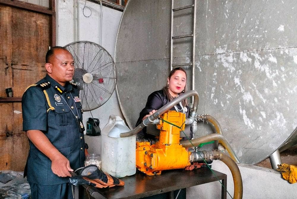 Norena (dua, kiri) menunjukkan peralatan yang digunakan bagi memindahkan minyak ke dalam tangki.