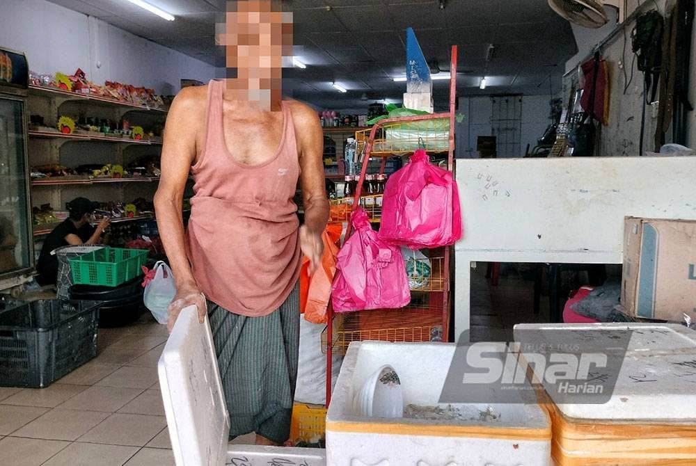Seorang pekerja Myanmar menunjukkan barangan basah yang terdapat di kedai runcit yang diuruskannya.