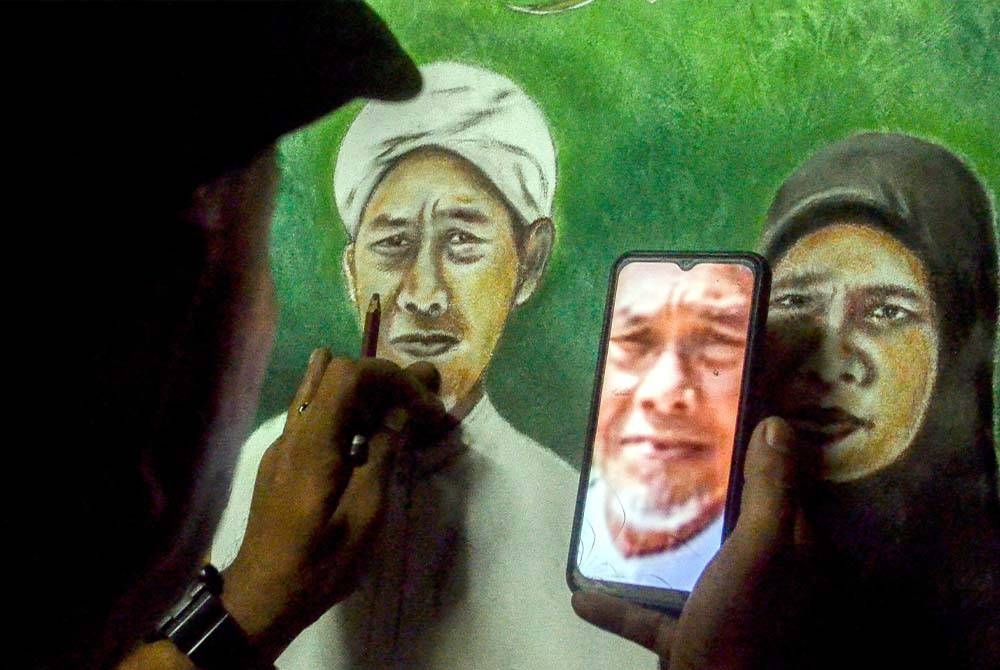 Ridzwan tekun merujuk gambar yang dihantar pelanggan untuk dilakarkan sebagai lukisan potret berwarna di kedai gunting rambut miliknya di Kampung Bertam Baru, Gua Musang, Kelantan. - Foto: Bernama