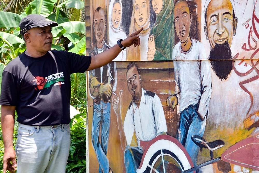 Ridzwan menunjukkan antara karyanya yang diabadikan di luar kedai gunting rambut miliknya di Kampung Bertam Baru, Gua Musang, Kelantan. - Foto: Bernama