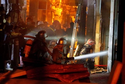 Anggota bomba giat memadamkan kebakaran dan menyelamat orang di blok apartmen di Hanoi pada Rabu - Foto: AFP