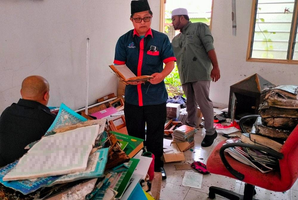 Kakitangan JAIM mengutip beberapa naskah AL Quran yang di letakkan di bawah.