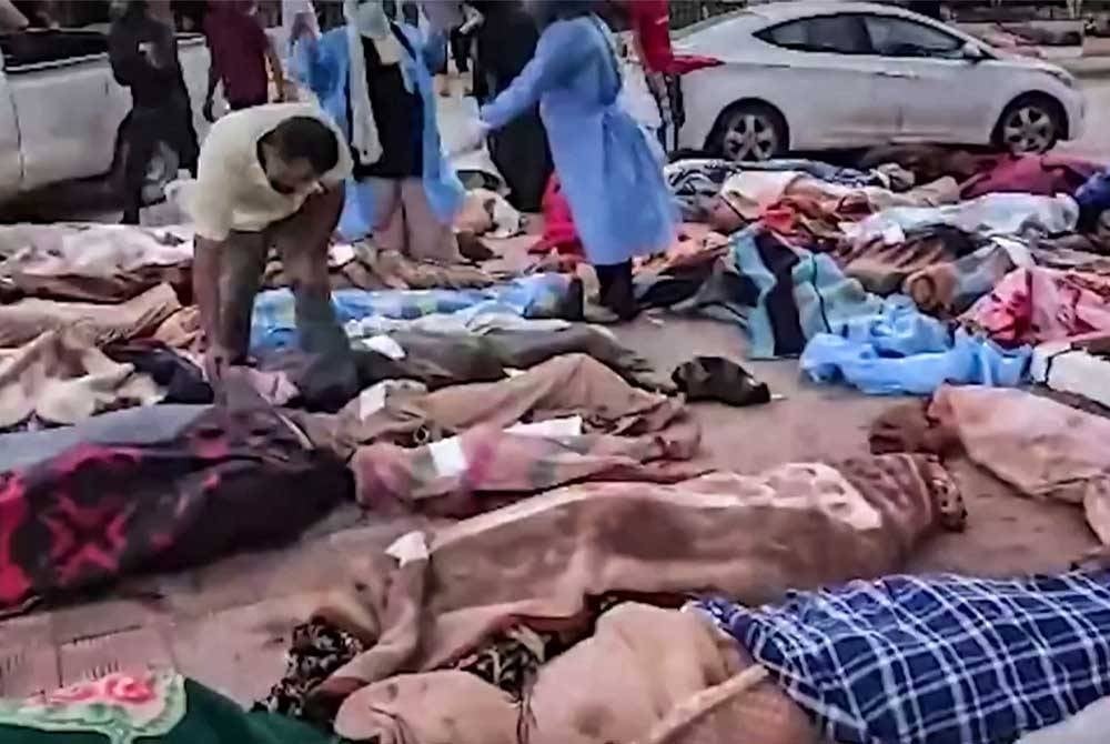 Puluhan mayat mangsa dikumpulkan di tepi jalan sebelum proses pengebumian beramai-ramai.