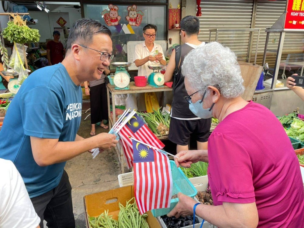 Dominic menyantuni pembeli di Pasar Awam Sungai Ara sempena Hari Malaysia pada Sabtu.