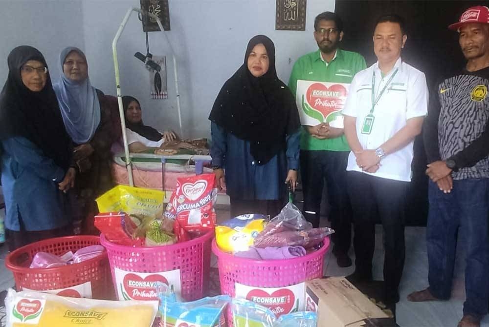 Zamzuri (dua dari kanan) menyampaikan sumbangan Econsave Prihatin kepada Nurizatul Nazura di Kampung Pancur, Pokok Sena.