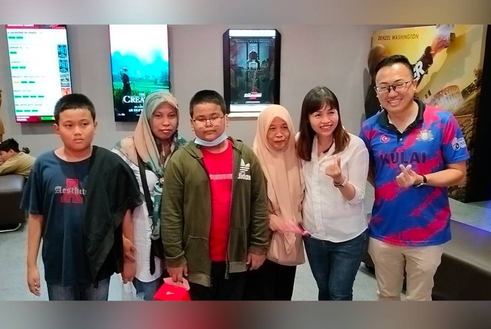 Nie Ching (dua dari kanan) bergambar dengan komuniti penduduk Kulai pada tayangan filem Malbatt Misi Bakara pada Ahad.