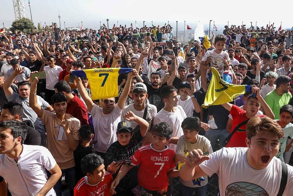 Penyokong bersorak di hadapan hotel yang didiami Ronaldo di Tehran, Iran. - Foto EPA