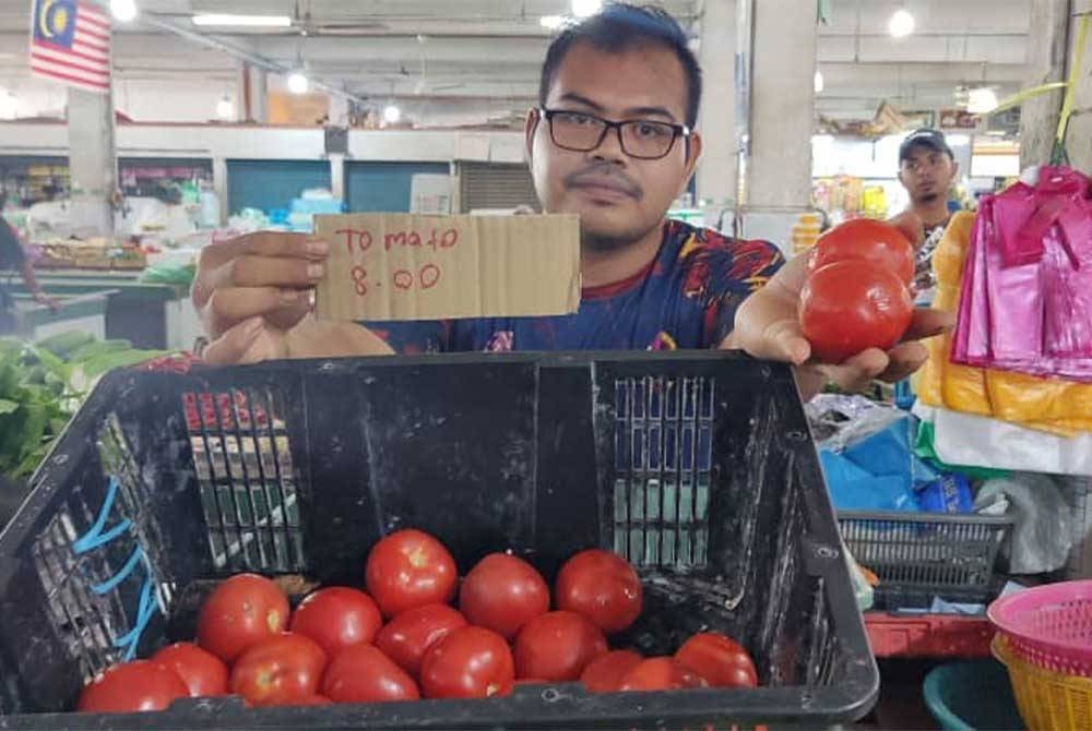 Asyraf Wajdi menunjukkan tomato yang dijual pada harga RM8 sekilogram di Pasar Besar Alor Setar pada Rabu.