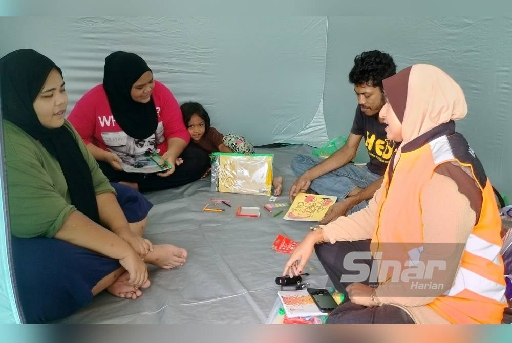 Siti Aisyah (kiri) dikunjungi Kanselor Jabatan Kebajikan Masyarakat semasa ditempatkan di PPS Masjid Islahiyah Tawar pada Jumaat.