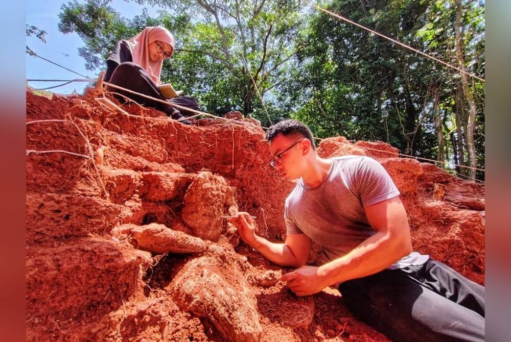 Seorang peserta penyelidikan sedang membersihkan arca yang ditemui.