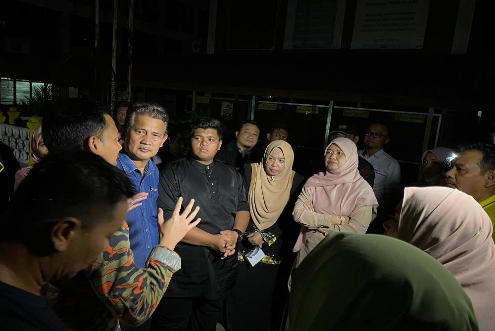 Fadhlina (kanan) mendengar taklimat kejadian kebakaran daripada pegawai Jabatan Bomba dan Penyelamat di SK Permatang To' Kandu, pada Jumaat.