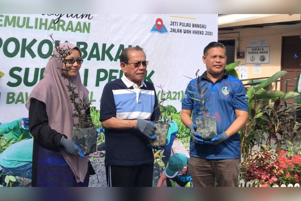 Saidi (kanan) bersama Meor Redwan (tengah) memberikan benih berembang untuk ditanam pada program penanaman pokok bakau di daerah Hilir Perak.