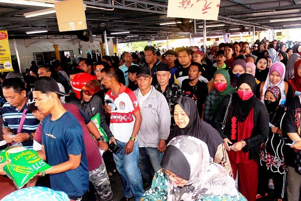 Orang ramai datang seawal 6 pagi untuk membeli beras putih import berjenama SITI dengan hanya RM1 pada Program Misi Jual Beras RM1 di Padang Kampung Dato' Seri Kamaruddin Manjung hari ini. Foto Bernama
