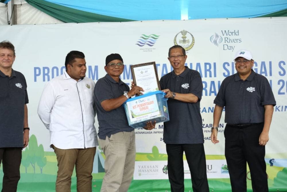 Ahmad Shahrir (kanan) mengiringi Mohammad Nizar (dua dari kanan) menyampaikan Kit Pemantauan Sungai kepada penduduk pada program sambutan Hari Sungai Sedunia 2023 peringkat negeri Perak dan pelancaran Sahabat Lembangan Sungai Kinta di Tanjung Rambutan pada Ahad.