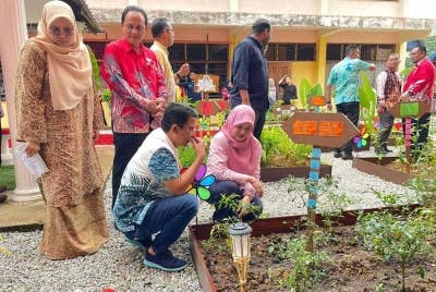 Fadhlina (duduk, kanan) melihat kebun yang diusahakan dalam program Pusat Pencegahan Kemiskinan Multidimensi di SK Sungai Acheh pada Ahad.