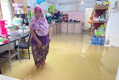 Azizah menunjukkan keadaan kawasan dapur rumahnya yang digenangi air selepas kediamannya dilanda banjir kilat.