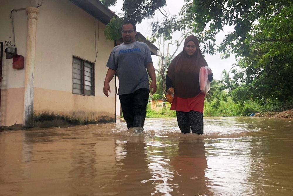 Mohd Azhan (kiri) bersama isterinya pulang untuk memeriksan keadaan rumah mereka di Kampung Nangmah, Changlun pada Selasa.