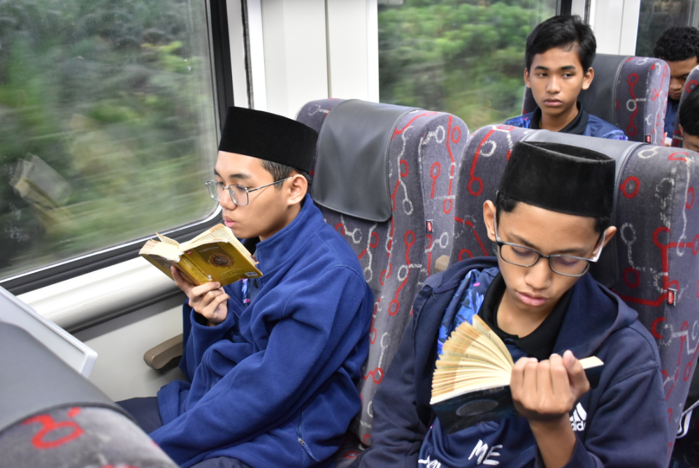 SEBAHAGIAN daripada 52 pelajar MRSM ATM Bera yang mengikuti program Me & My Quran Train to Dabong membaca sambil menghafaz al-Quran ketika dalam perjalanan dari Stesen Keretapi Triang di Bera, Pahang ke Dabong, Kelantan pada Sabtu lalu.