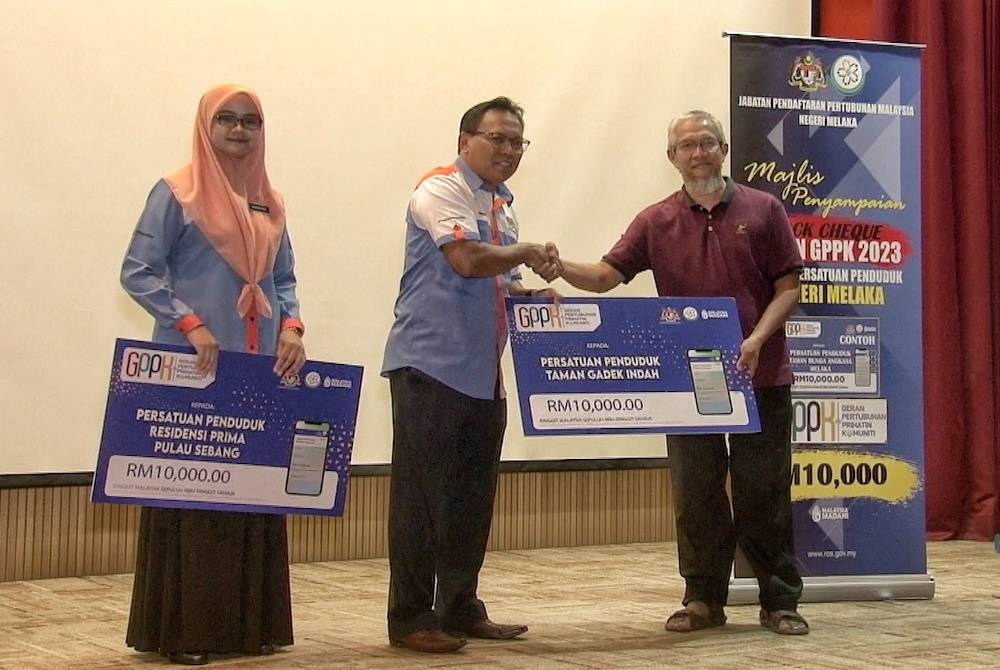 Mohd Nawardi (tengah) menyampaikan replika cek GPPK kepada salah seorang wakil pertubuhan di Kompleks Kementerian Dalam Negeri (KDN) Melaka, di Ayer Keroh, di sini, pada Selasa.