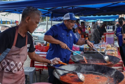 Amizar beramah mesra bersama peniaga sempena kempen PRK DUN Pelangai di tapak pasar malam Felda Chemomoi pada Ahad. - Foto Bernama
