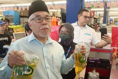 Hassan menunjukan minyak masak yang masih ada tetapi dihadkan penjualnnya semasa melakukan tinjauan bekalan bahan makanan bersama pegawai KPB dan KPDN Johor di Pasar Raya Maslee Taman Cendana, Pasir Gudang pada Selasa.