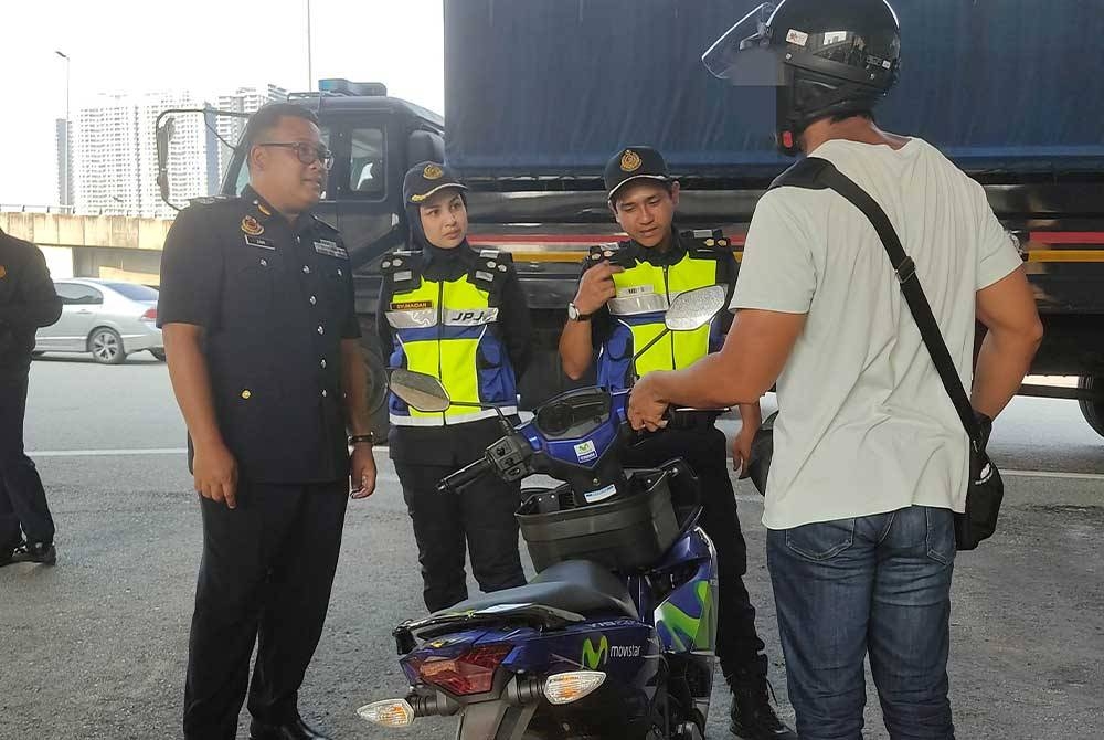 Mohd Zaki (kiri) menjalankan pemeriksaan ke atas penunggang motosikal semasa Op Sepadu di Plaza Tol Sentul Pasar, Kuala Lumpur pada Rabu.