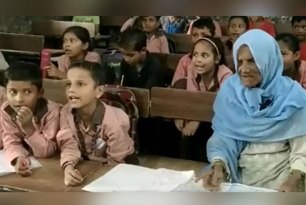 Salima Khan (kanan) belajar membaca bersama rakan sekelas yang lapan dekad muda daripadanya di sebuah sekolah rendah di Bulanshahr, Uttar Pradesh. - Foto Agensi