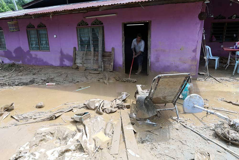 Penduduk di Kampung Padang Empang membersihkan lumpur di kediaman masing-masing selepas ditenggelami banjir malam tadi.