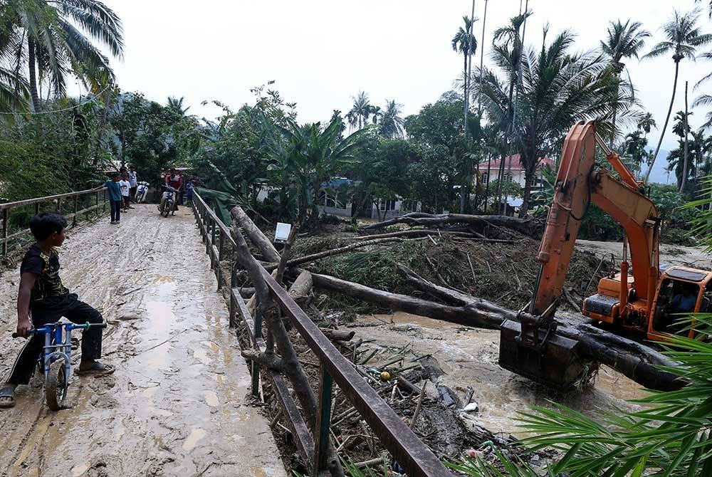 Penduduk Kampung Padang Empang melihat kerja-kerja pembersihan sisa pokok dan batang kayu yang tersangkut pada jambatan susulan kejadian banjir malam tadi.
