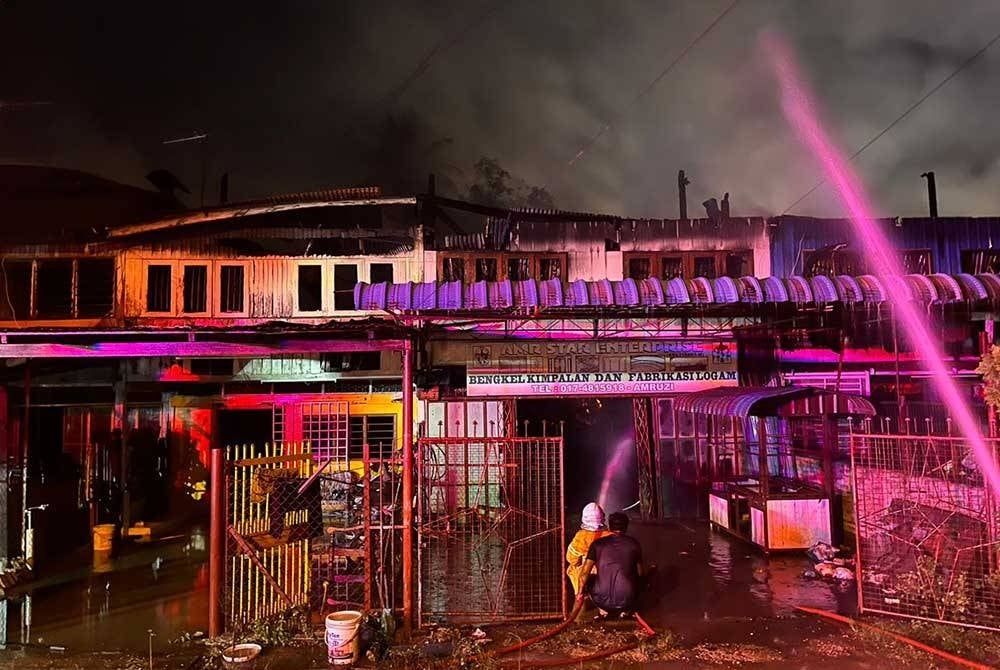 Anggota bomba dari BBP Jitra memadamkan kebakaran deretan kedai di Kampung Sungai Korok, di sini awal pagi Jumaat.