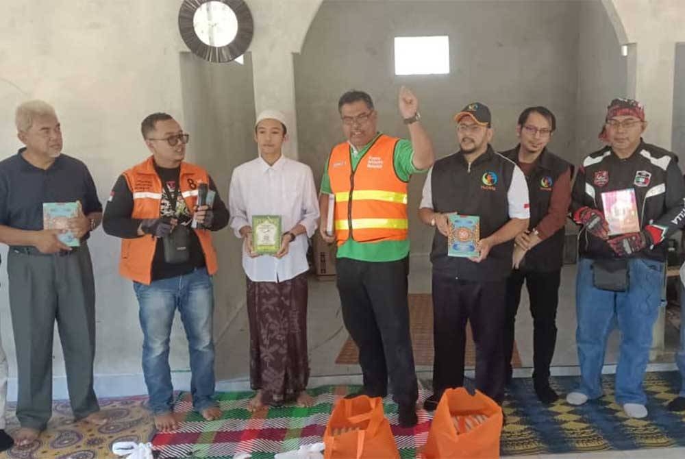 Rozi (tiga dari kanan), Mas Imran (tengah) dan Hashim (kiri) menyerahkan sumbangan dan al-Quran kepada pelajar tahfiz di Taman Pendidikan Al-Quran Al-Batsa , Dusun Batu Santek, Desa Pengadangan, Lombok Timor, Lombok, Indonesia pada Jumaat.