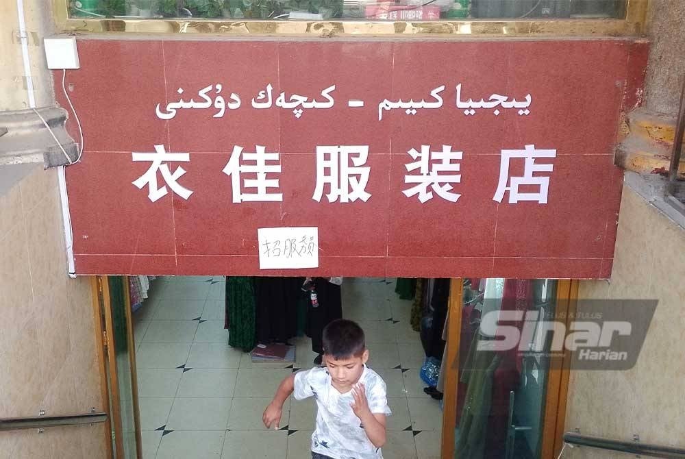 Papan tanda dengan tulisan jawi dan mandarin tertera di sebuah premis menjual pakaian.