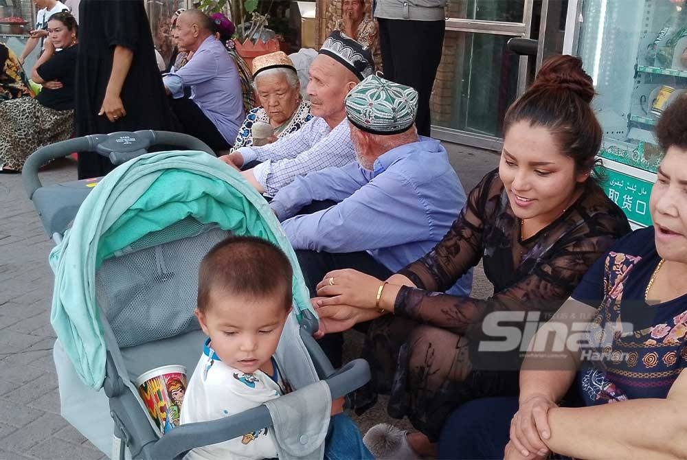 Sebuah keluarga Uighur berehat di kawasan kaki lima di bandar purba Kashgar.