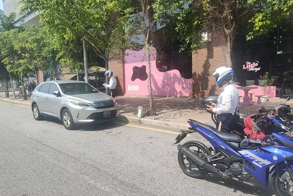 Anggota trafik PDRM mengenakan saman kepada pesalah lalu lintas semasa Op HUU di sekitar ibu kota pada Jumaat.