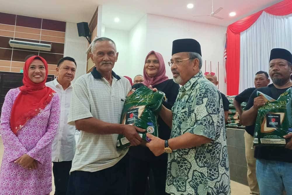 Tajuddin (dua dari kanan) menyampaikan sumbangan beras anjuran Pasir Salak Bangkit kepada 500 keluarga di Dewan Besar Pekan Rabu, Chenderong Balai pada Sabtu.