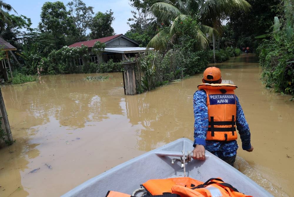 Anggota Angkatan Pertahanan Awam (APM) Kota Setar menjalankan operasi menyelamat mangsa-mangsa banjir dari Kampung Bukit, Mukim Derang. - Foto Bernama