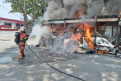Anggota bomba sedang memadamkan bas yang terbakar dalam kejadian di Jalan Tandang di sini pada Ahad.