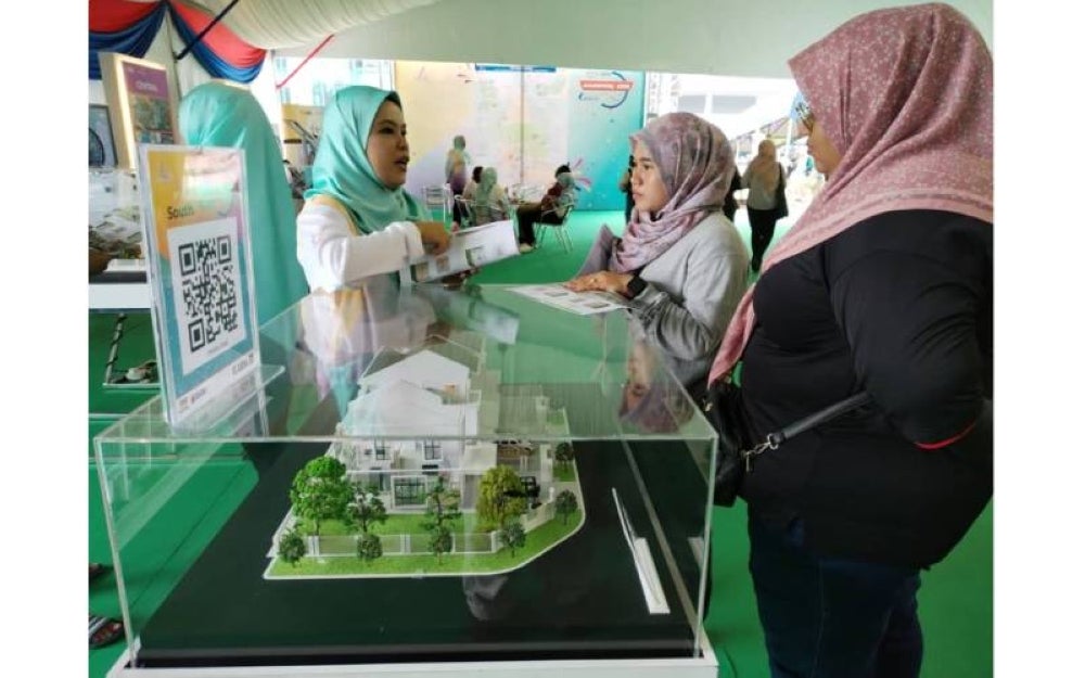 Dua pengunjung mendengar dengan tekun penjelasan dari seorang petugas Karnival UDA 2023 @ Angsana Johor Bahru Mall.