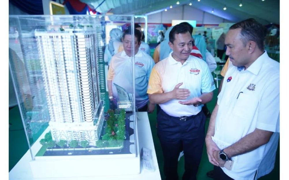 Mohd Salem (dua, kanan) menerangkan kepada Mohd Jasni berkenaan hartanah UDA yang ditawarkan kepada bakal pembeli.