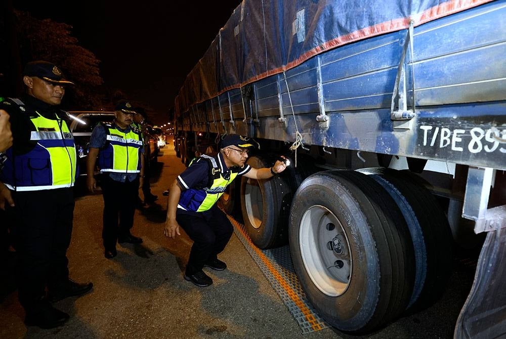 Lokman (kanan) memeriksa tayar kenderaan berat pada Majlis Pelancaran dan Pelaksanaan Operasi Kenderaan Komersial di Plaza Tol Kemuning Lebuh Raya KESAS hari ini. Foto Bernama
