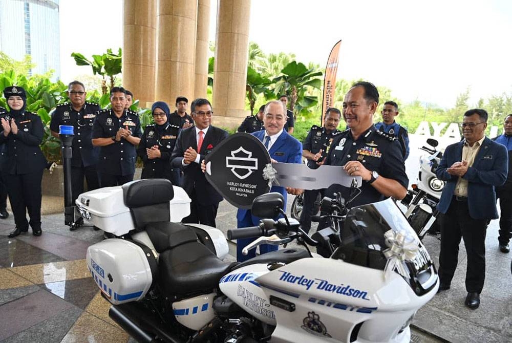 Hajiji (dua dari kanan) menyerahkan replika kunci motosikal kepada Jauteh (kanan) pada majlis penyerahan motosikal Harley Davidson di pekarangan Menara Kinabalu pada Selasa.