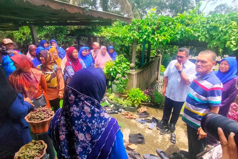 Adnan (kanan) bersama Amizar ketika menyantuni orang ramai di kediaman Ketua UMNO Cawangan Felda Kemasul, Roslan Alias pada Selasa.