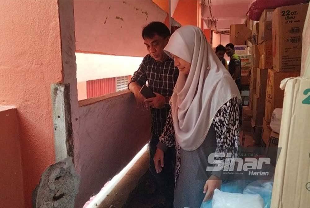 Dr Hafidzah melihat bahagian dinding bangunan yang perlu diselenggara.