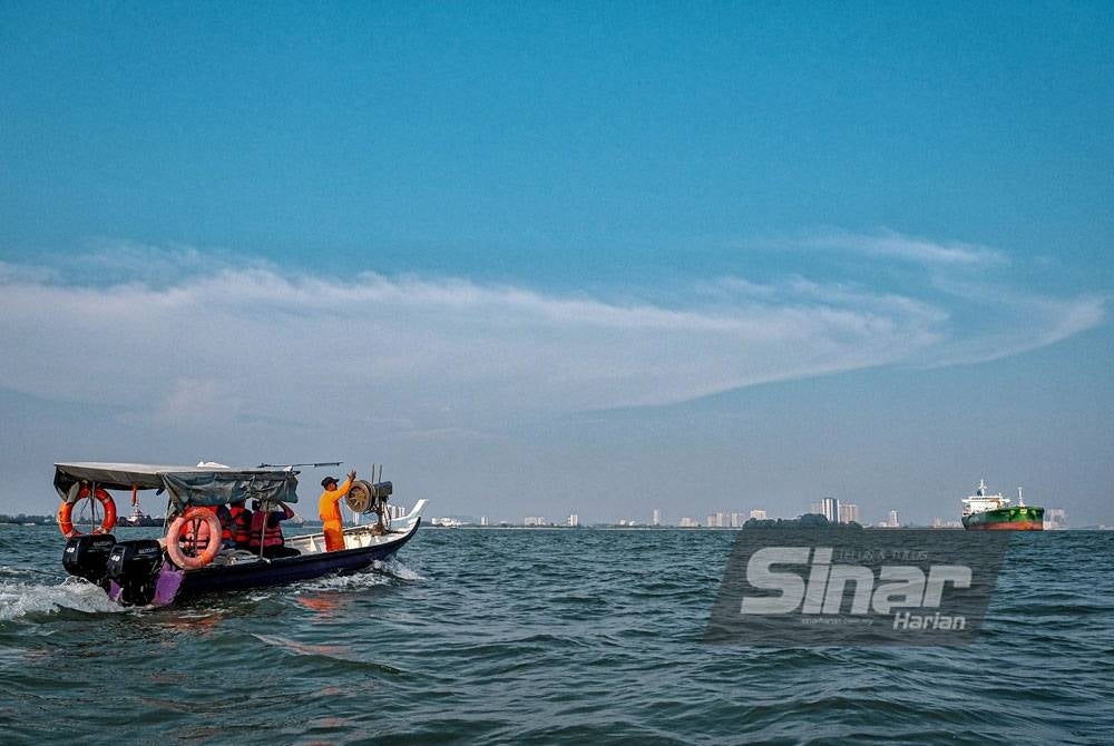 Nelayan meninjau kapal dagang yang berlabuh di perairan Tanjung Kling, Melaka, hingga menjejaskan hasil tangkapan mereka.